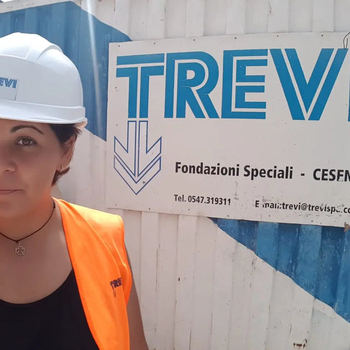 Lavoratore edile con casco bianco e gilet arancione in Trevi Group durante Master Ingegneri.