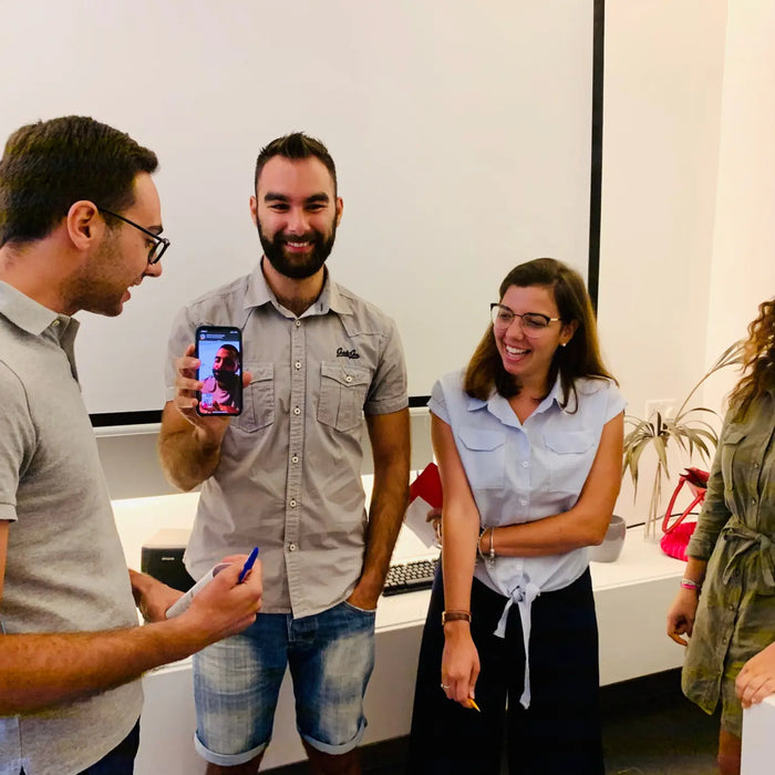 Gruppo di persone in conversazione con smartphone, focus su Italiana Costruzioni.