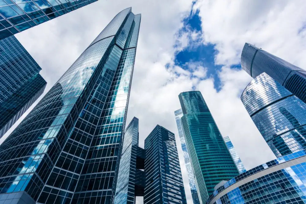 Moderni grattacieli di vetro sotto cieli blu, simbolo di contratti pubblici nel Codice Appalti.
