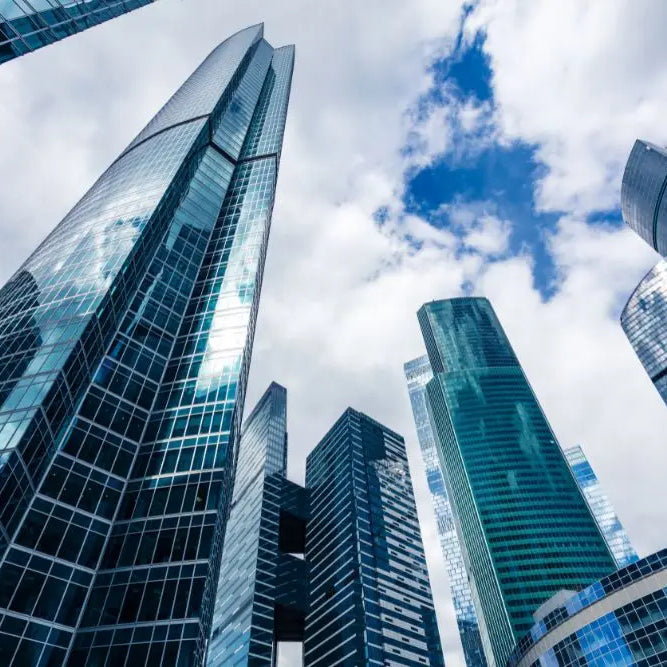 Moderni grattacieli di vetro sotto cieli blu, simbolo di contratti pubblici nel Codice Appalti.