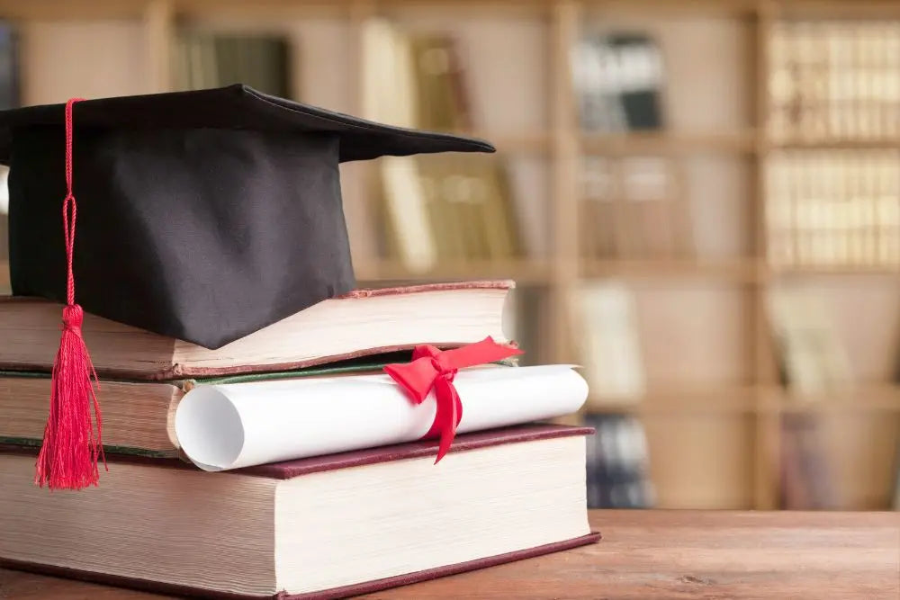 Capello di laurea e diploma su libri per riscatto laurea agevolato nel 2025.